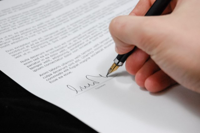 Main signant un document au stylo plume